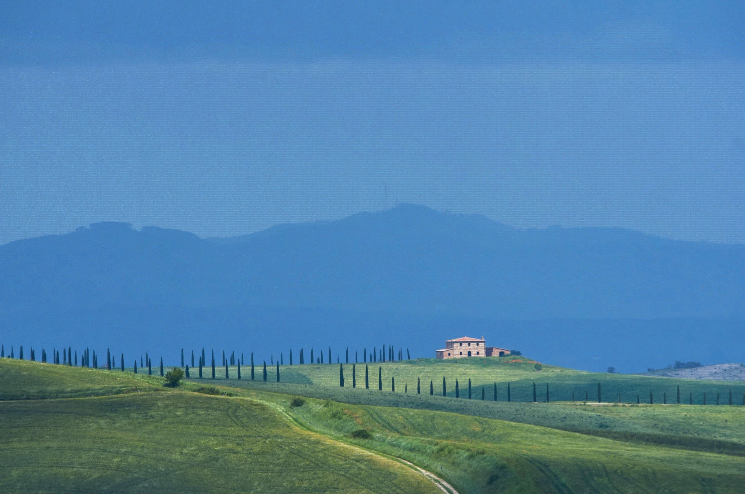 Rolling Tuscan hills with a stone villa framed by cypress trees